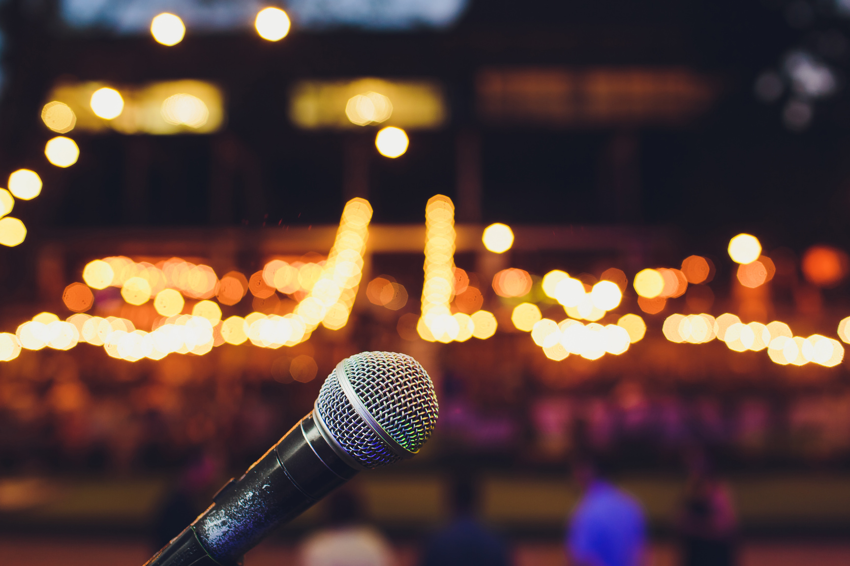 microphone on a stand up comedy stage with colorful bokeh , high contrast image.